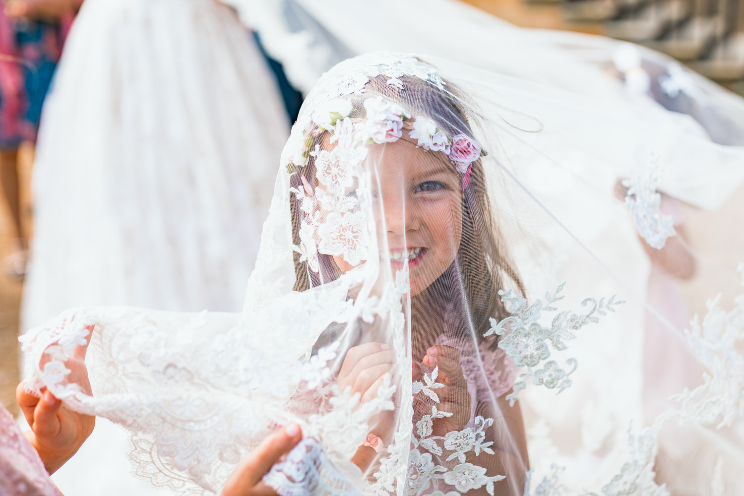 flower girl smiling under wedding veil
